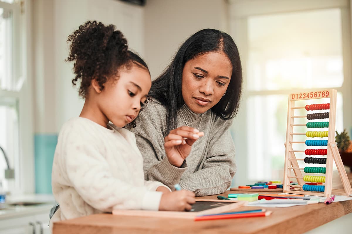Teacher assisting young girl with abacus.