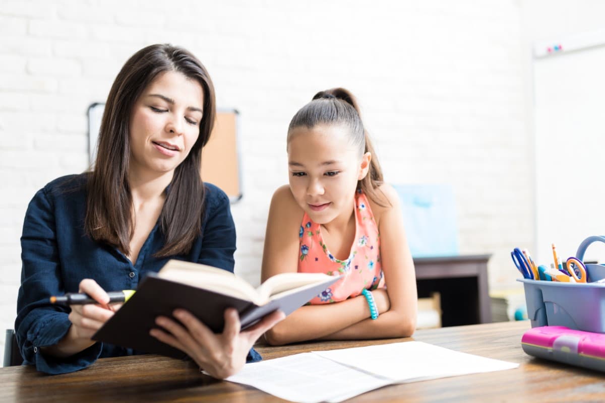 Teacher reading to single student in classroom setting