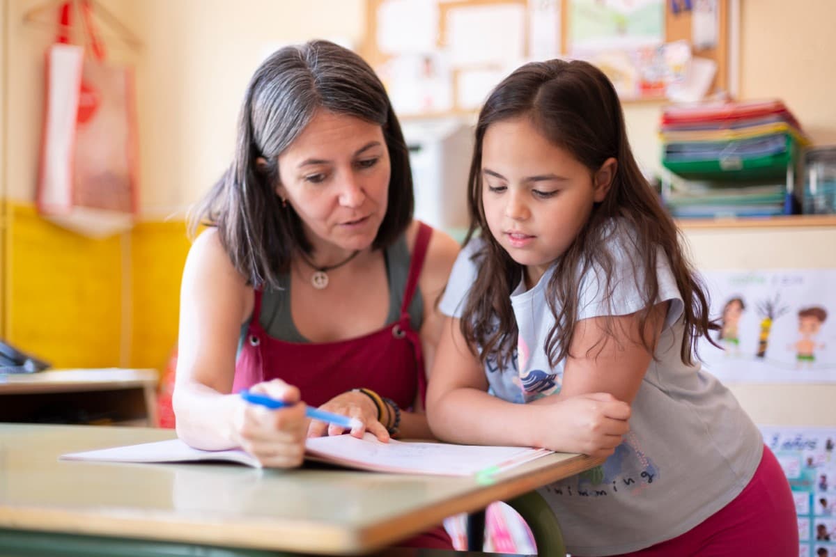 K-12 teacher reading with a student in a classroom