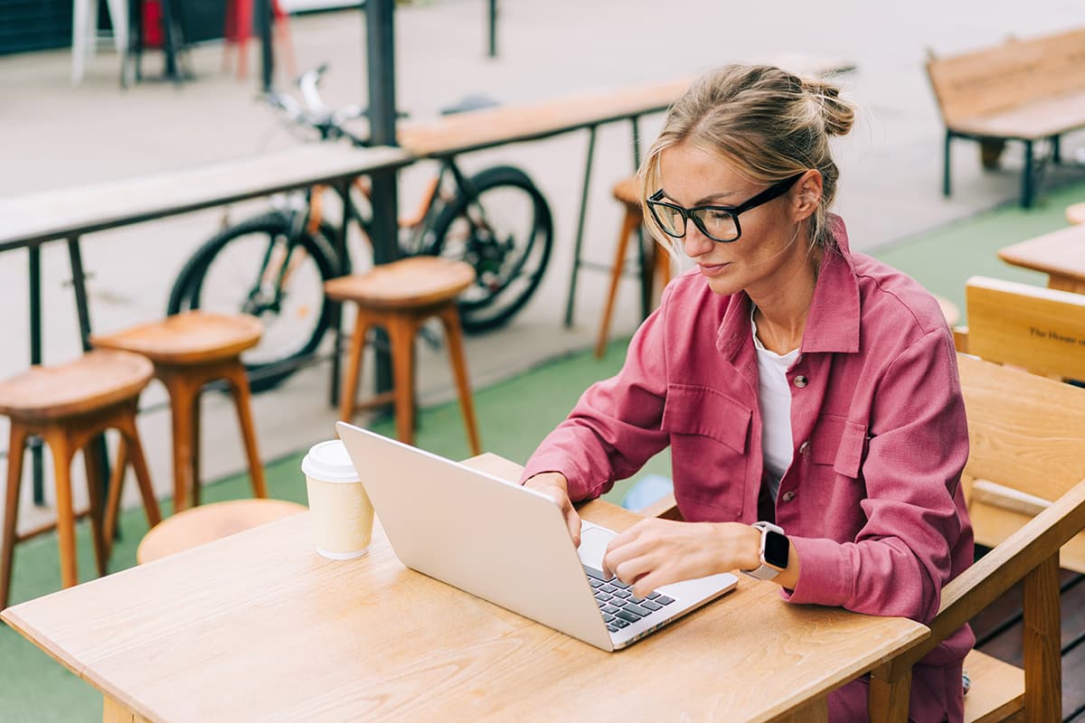 Woman on laptop at outdoor cafe.