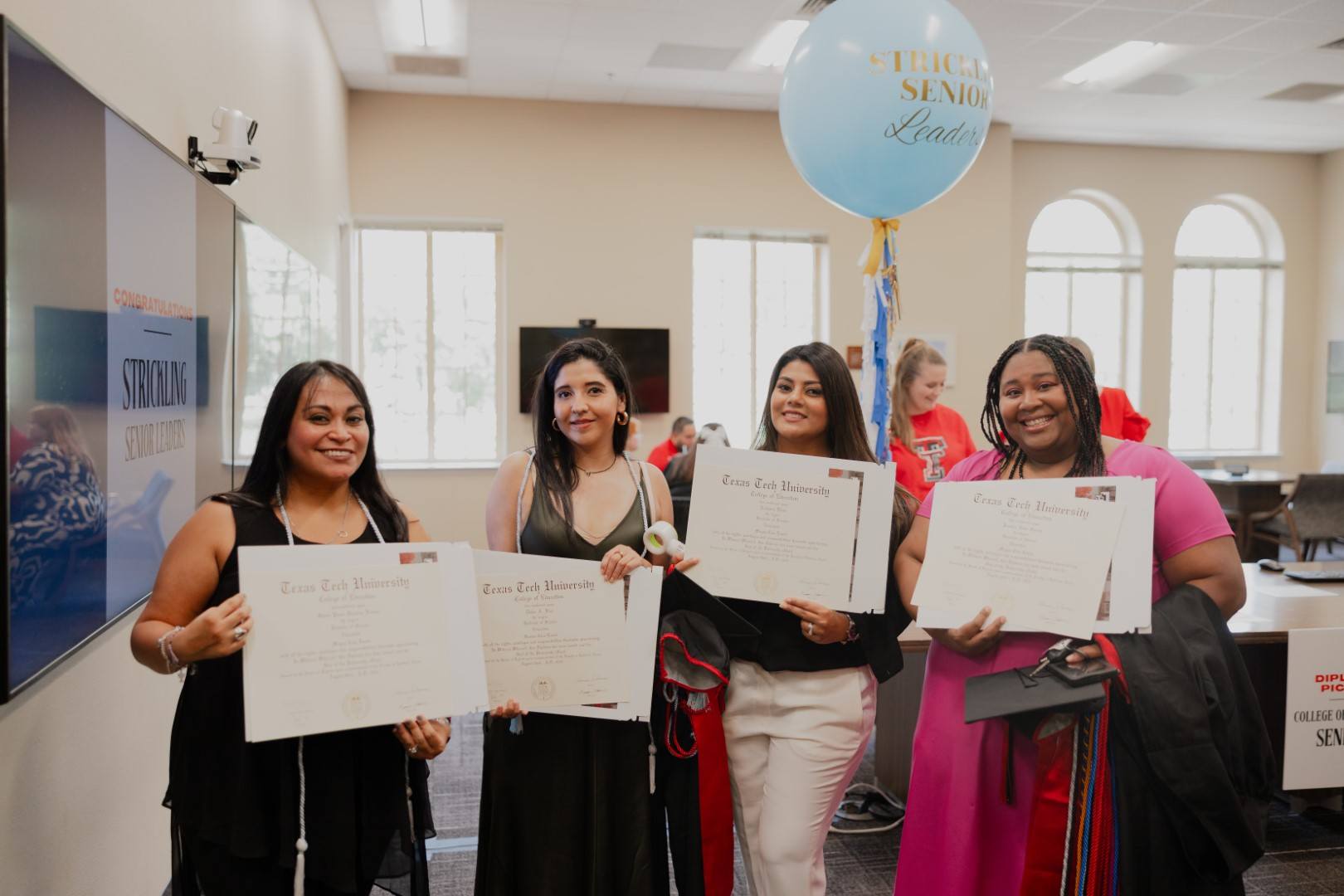 photo of four students holding their diplomas at the undergraduate reception