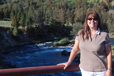 Gina Covington standing next to red railing with trees and a river in the background