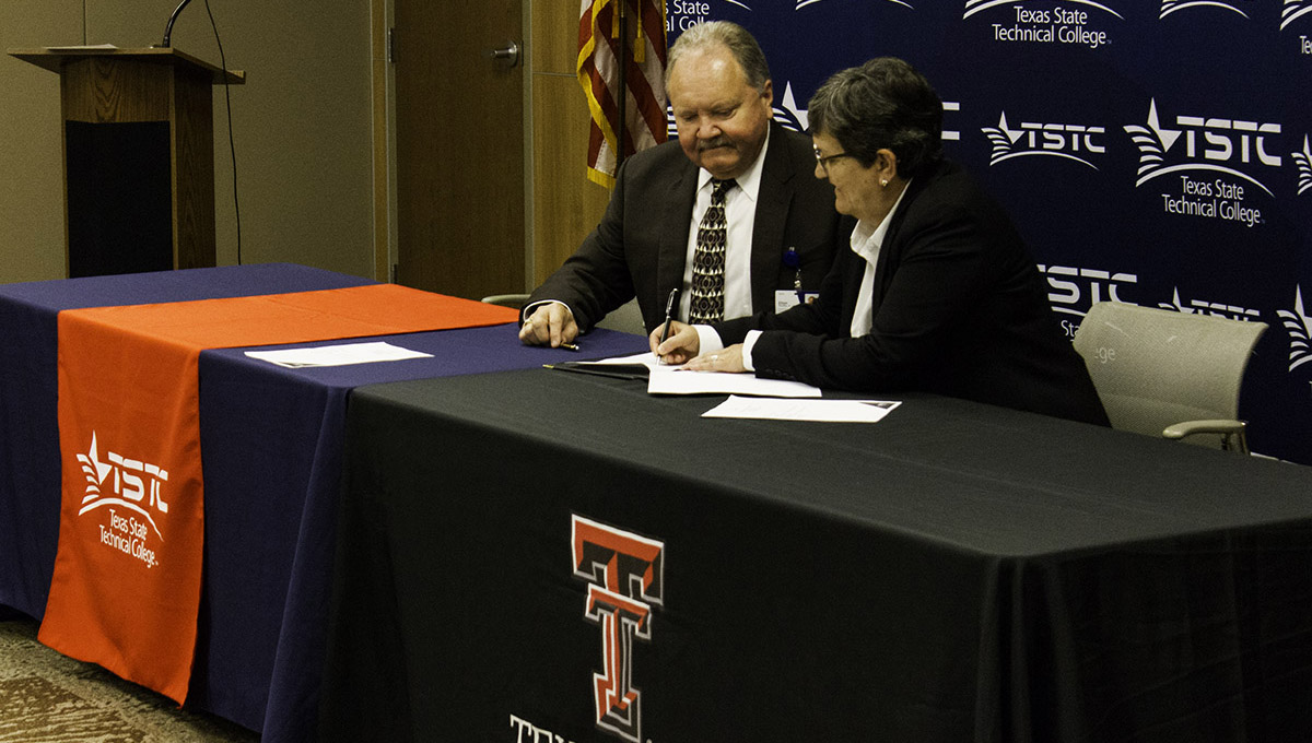 A representative from tstc and a representative from TTU sit side-by-side behind rectangular tables that are both covered in draping with their school's logos