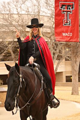 The Masked Rider sits on top of Fearless Champion while using her right hand to show the guns up symbol