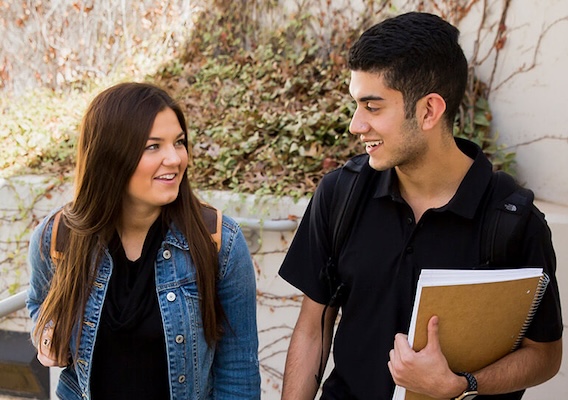 two students talking to each other as they walk up stairs