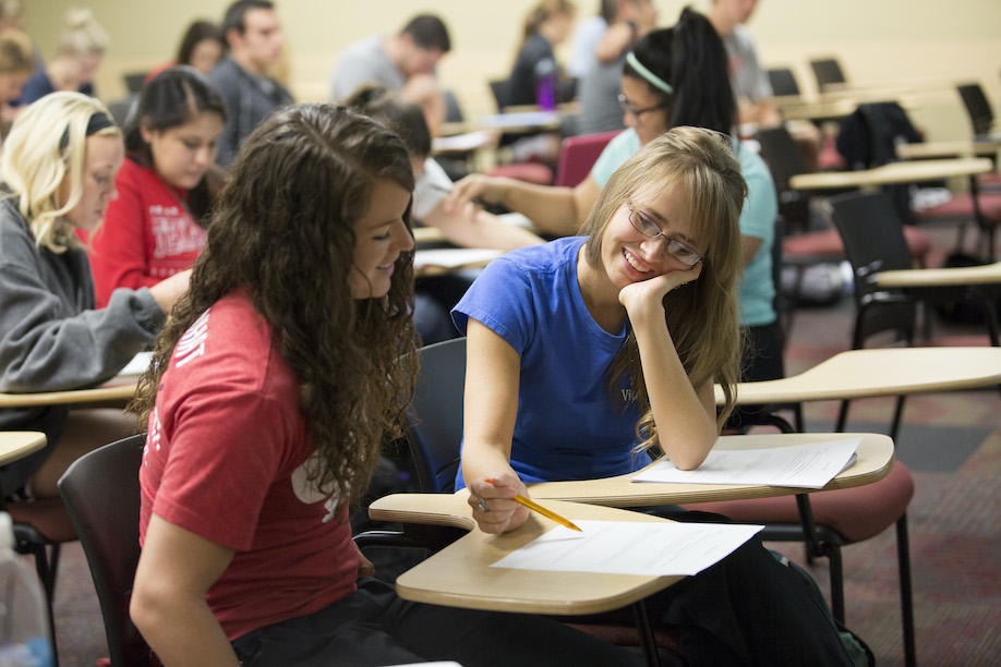 two young women at a desk working on homework together