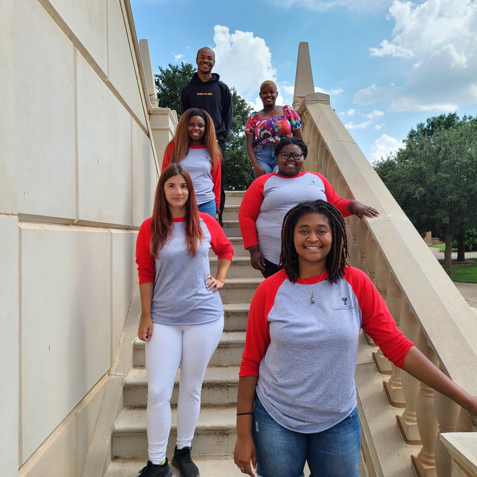 six students standing on stairs, looking at camera