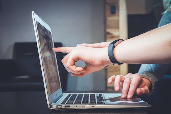 an open laptop with a hand pointing at the screen