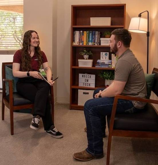 A staff member meeting with a student in an office.