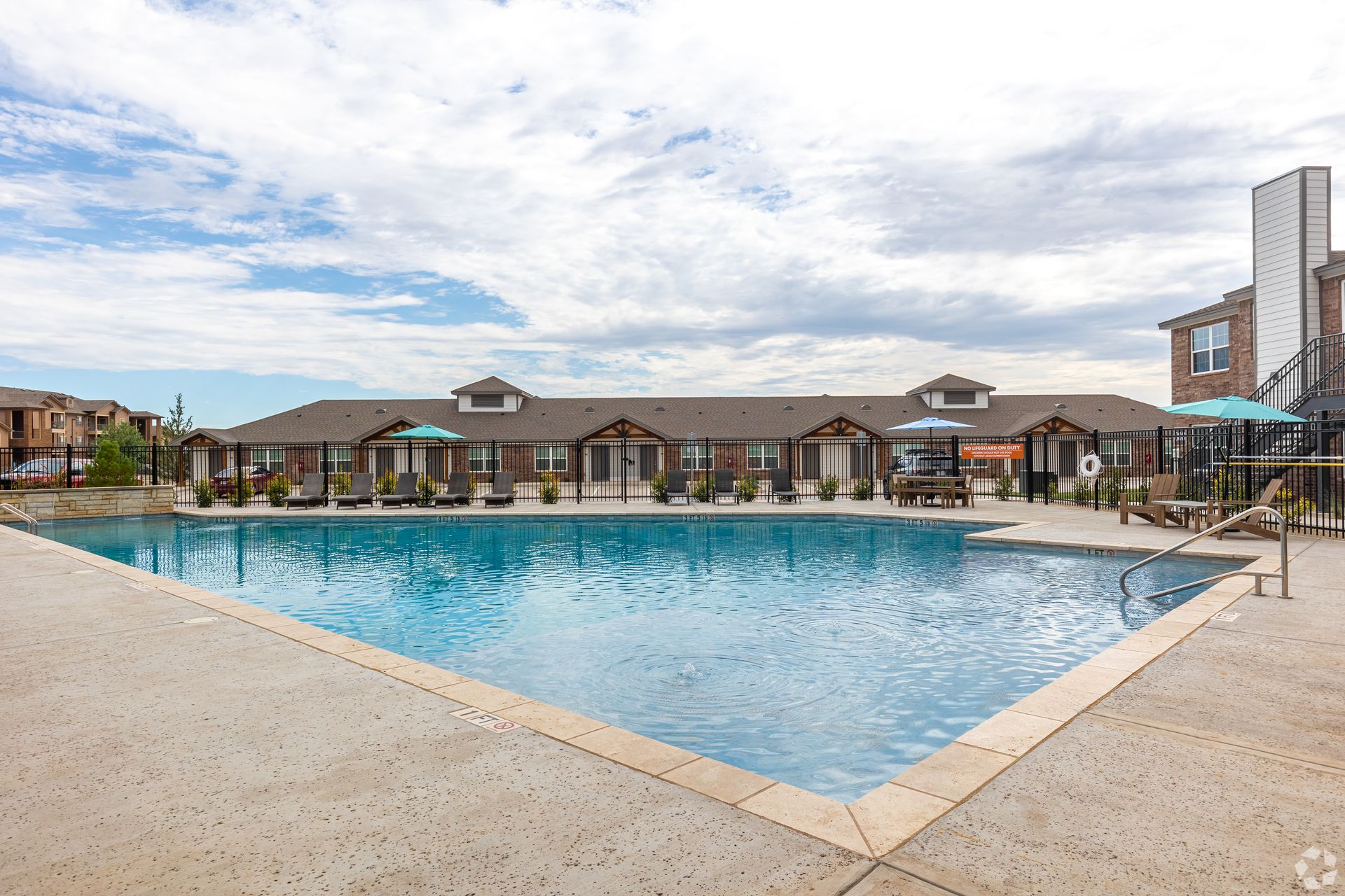 Outdoor swimming pool with lounge chairs, umbrellas, and fenced deck at Monarch Point.