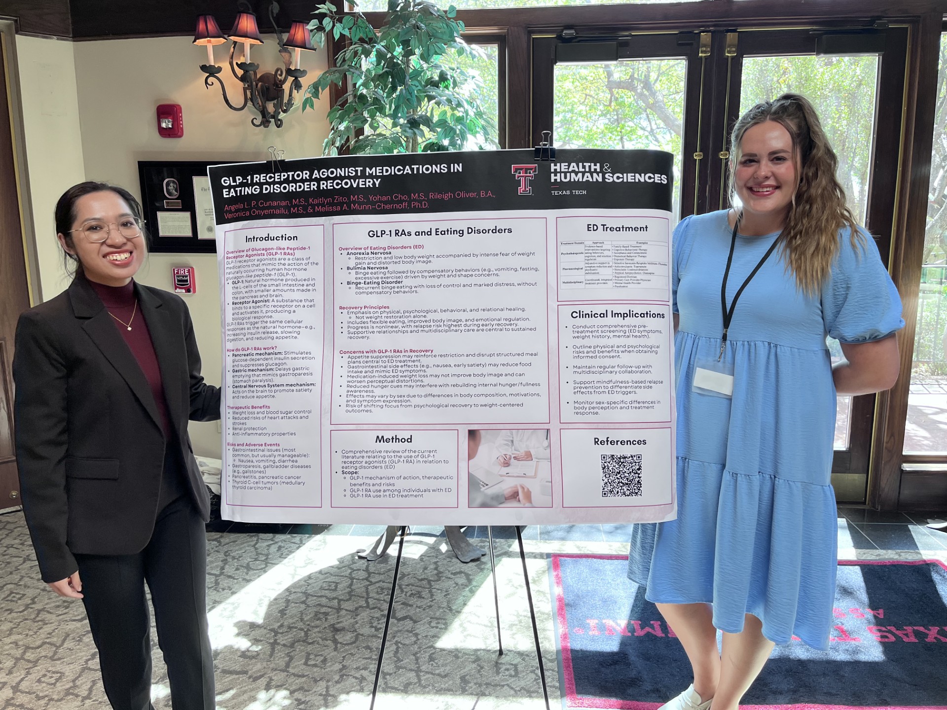 Angela and Kaitlyn next to McKenzie Lectureship poster