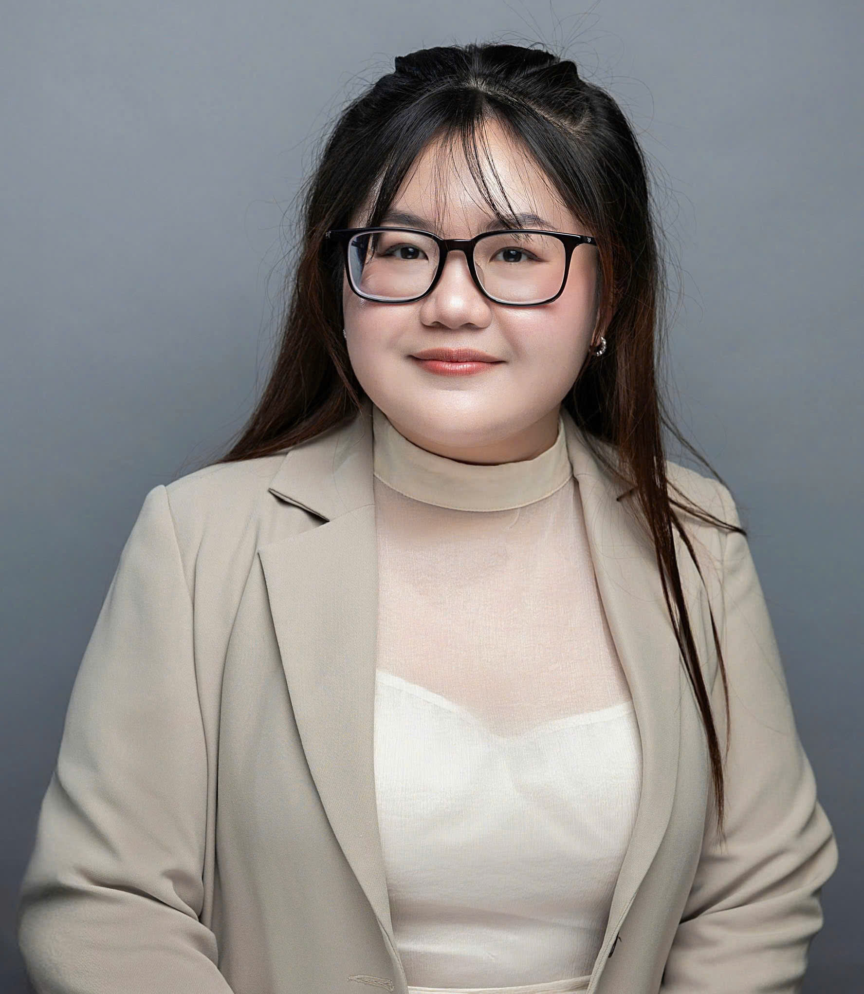 Ngoc Tran Nguyen wearing tan blazer and glasses looking at camera