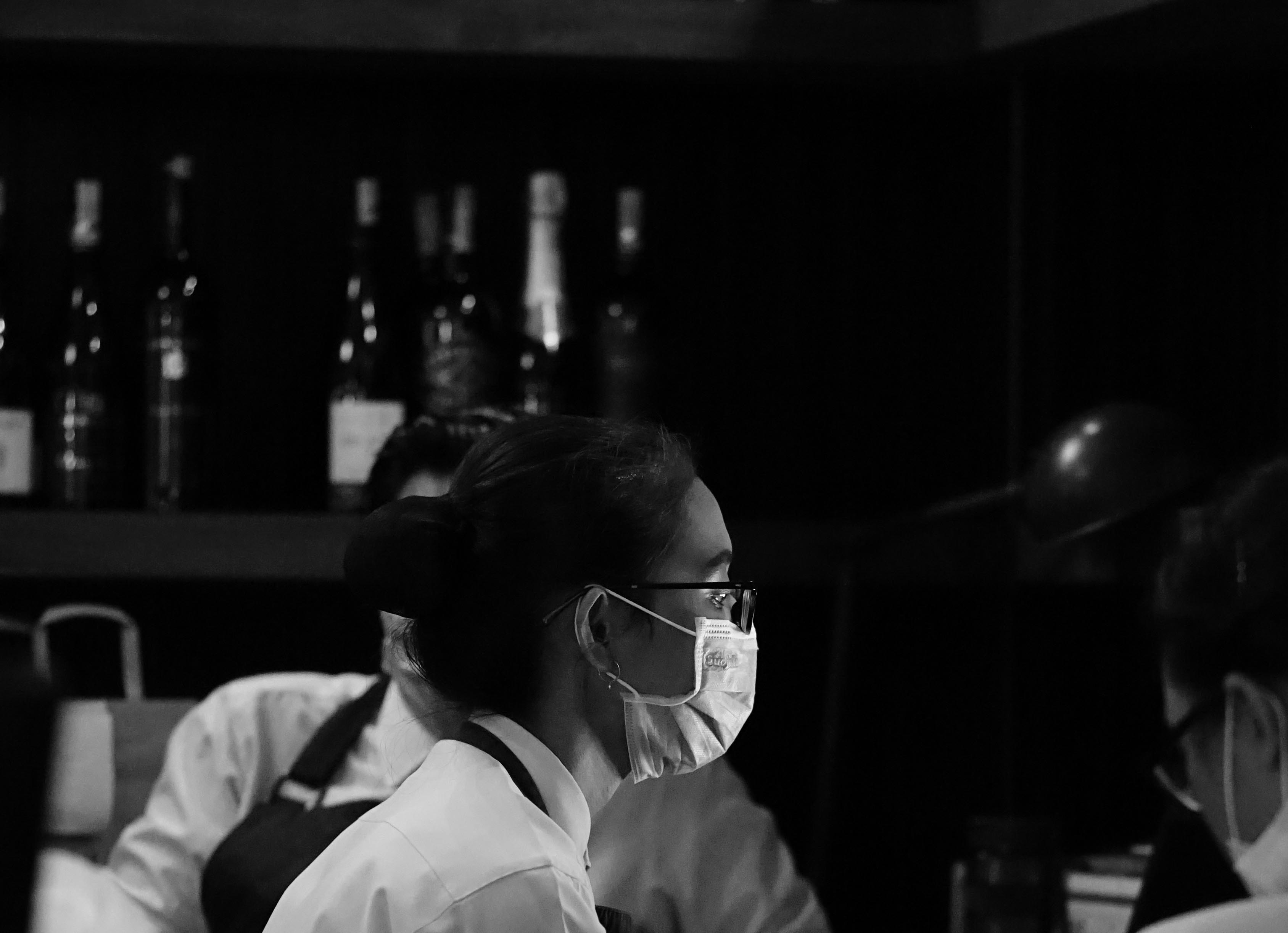Server with mask and shelf of wine