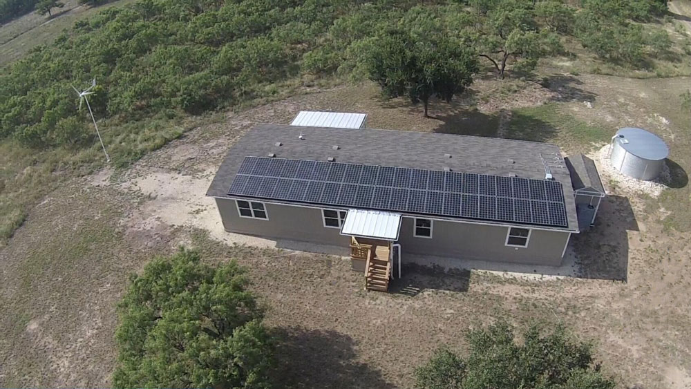 aerial view of home with solar panels, shed, wind turbine and water catchment tank