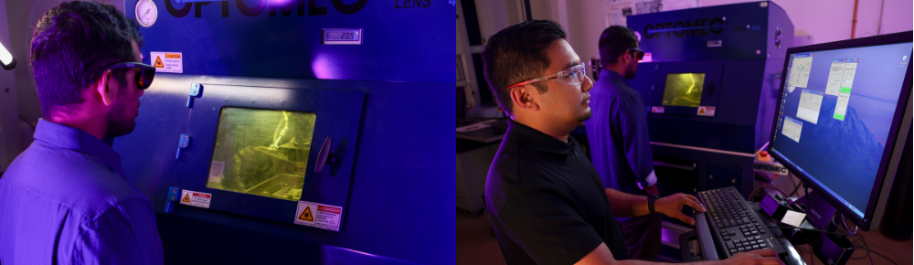 Students standing in front of machines looking into machine, one student looking at computer screen.