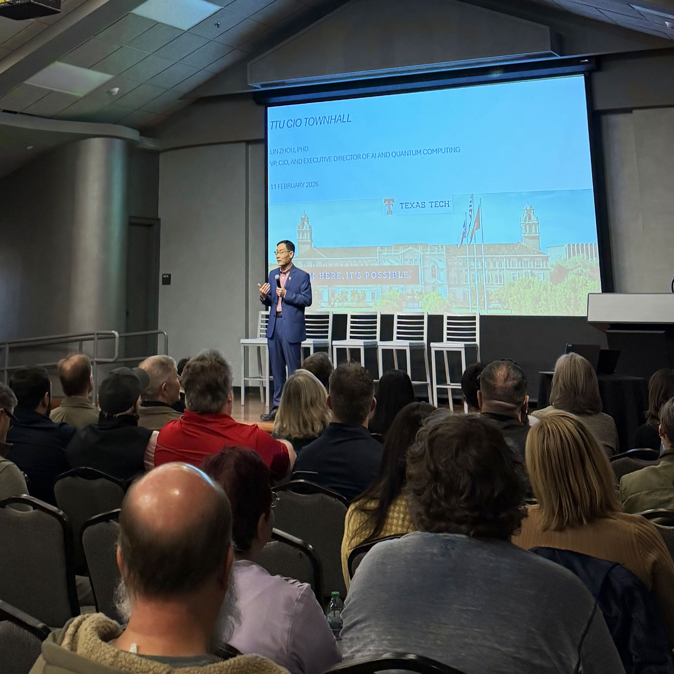 CIO Dr. Lin Zhou standing on a stage addressing the audience at the CIO Town Hall.