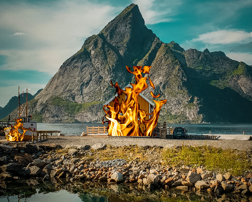 A small house and boat are on fire along a rocky shoreline. A large mountain towers above the house in the background.