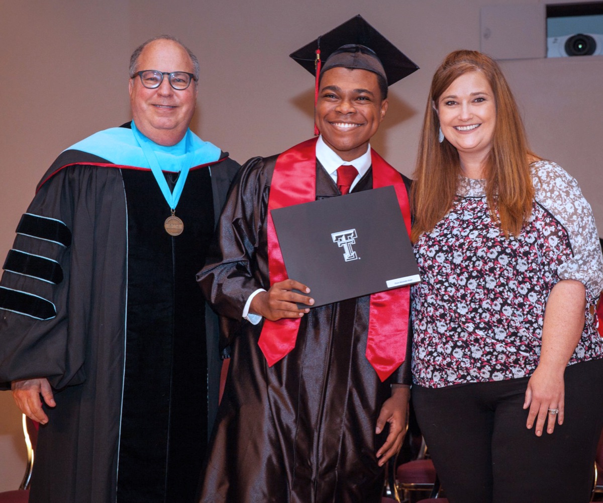 Chase holds his diploma, flanked by TTU K-12 administrators.