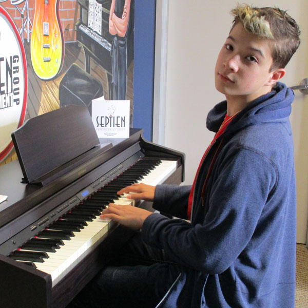 Austin Chatfield playing piano in the Septien Entertainment Group lobby.
