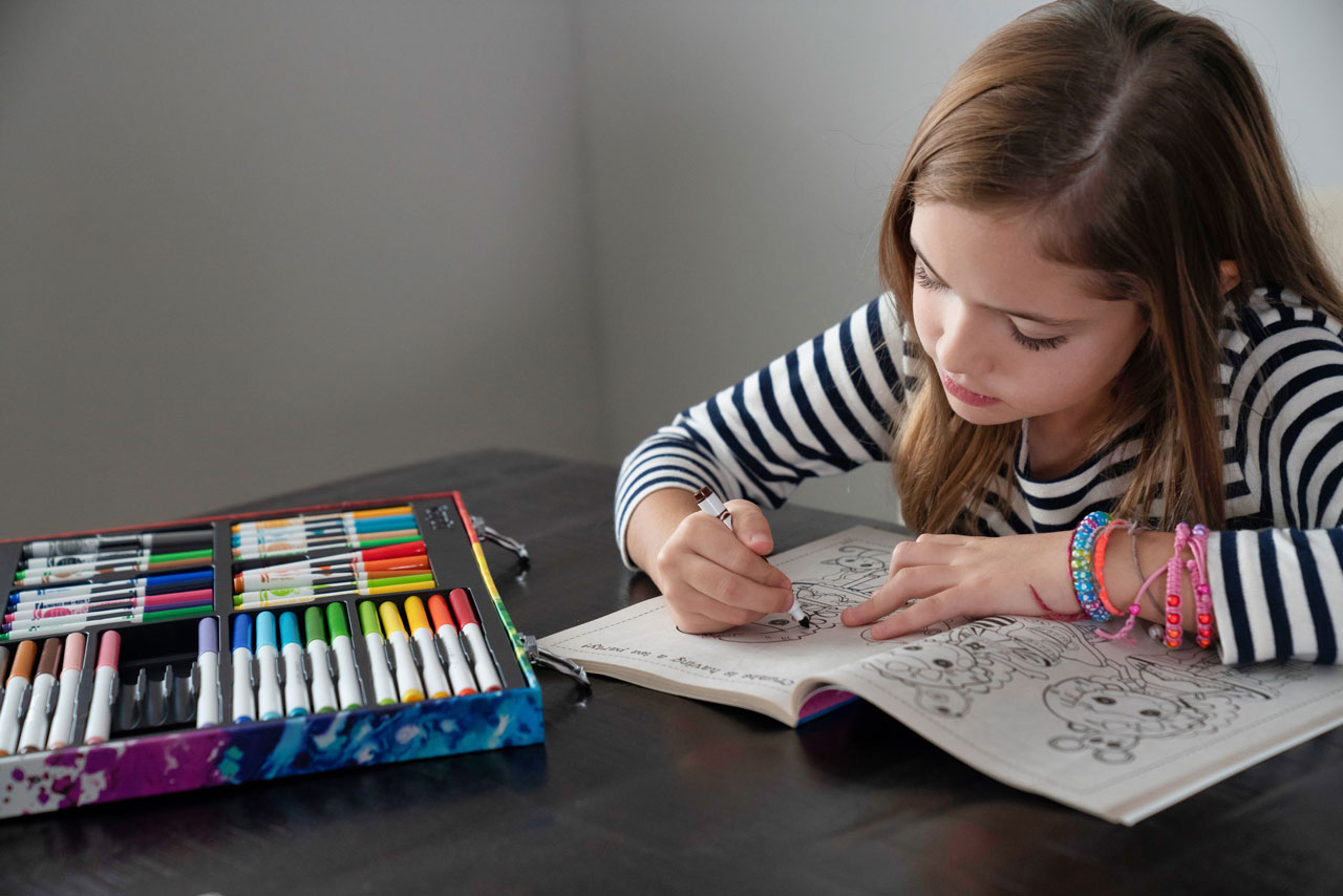 Photo of Tenlee Nyman filling in a coloring book with markers.