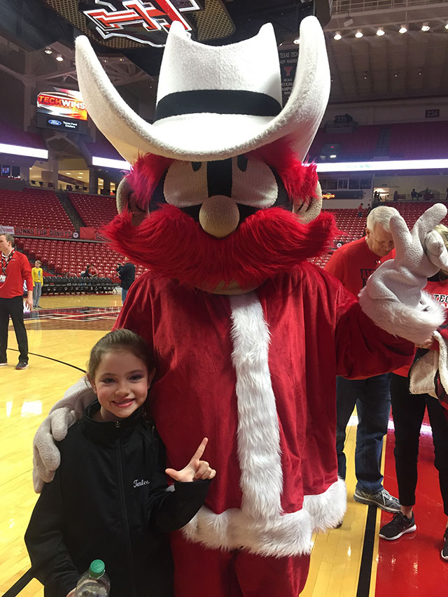Tenlee Nyman with Raider Red dressed like Santa Claus on the basketball court in the United Supermarkets Arena.