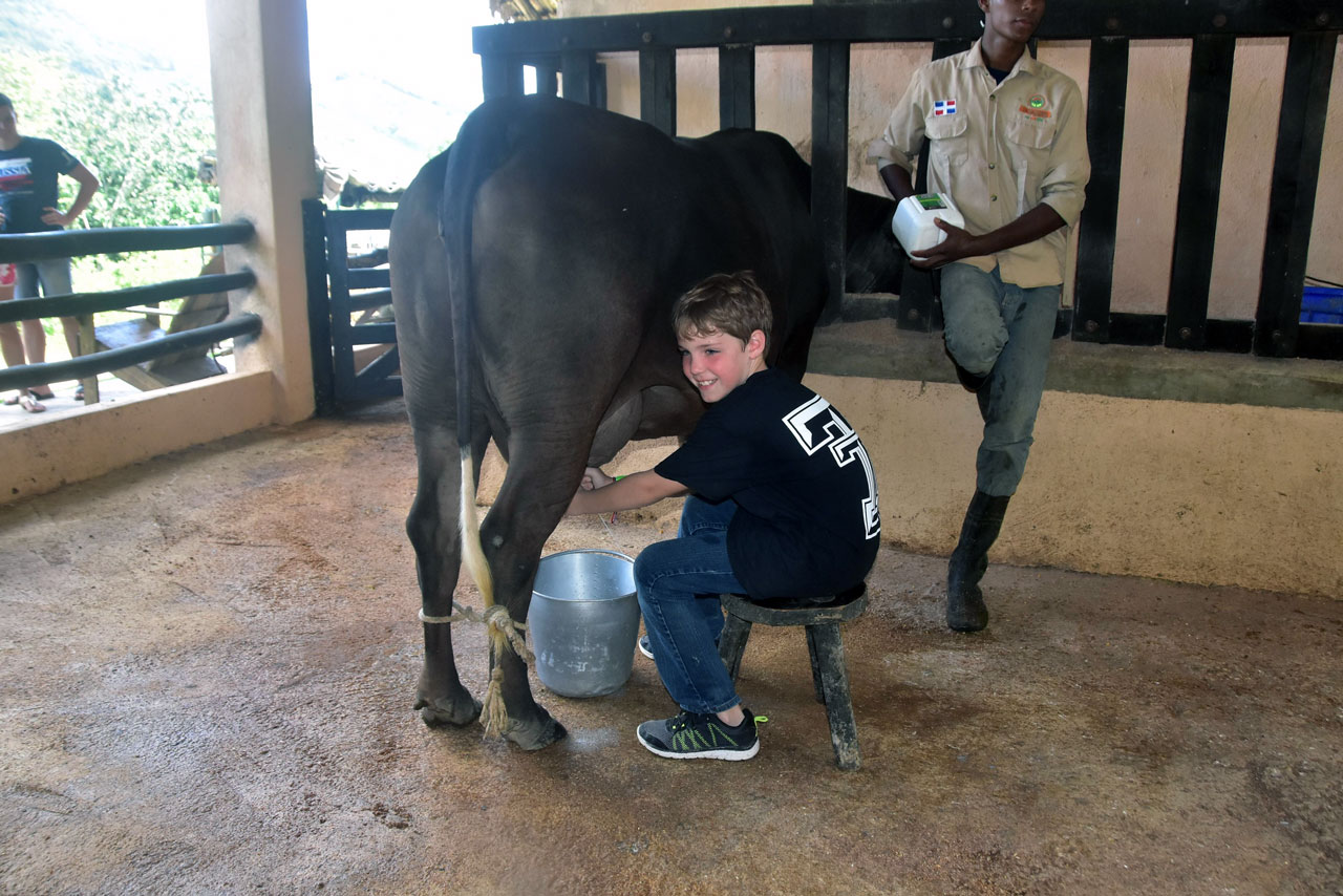 Travis milking a cow at La Hacienda Park, Dominican Republic.