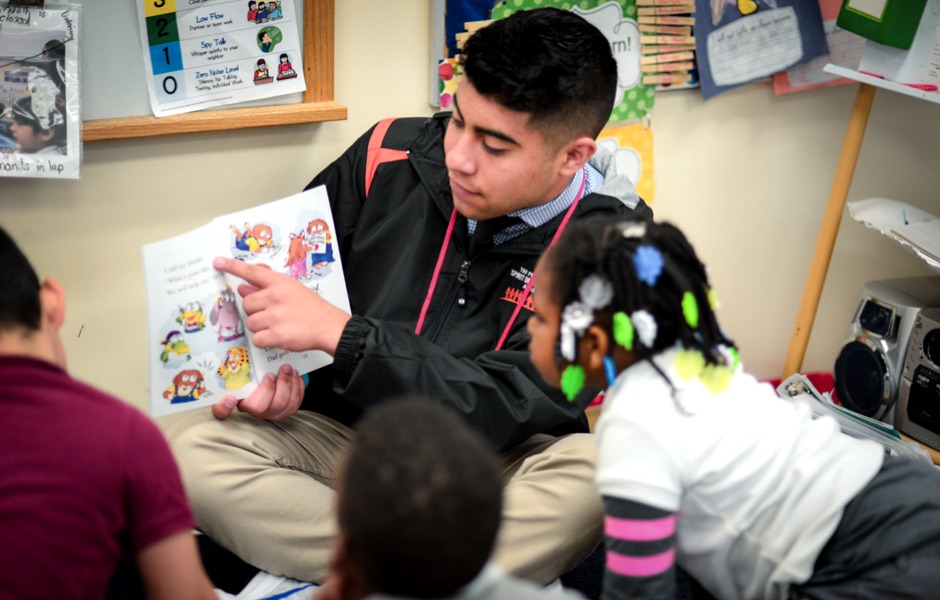 Photo of Ryan Almusawi reading to kids.