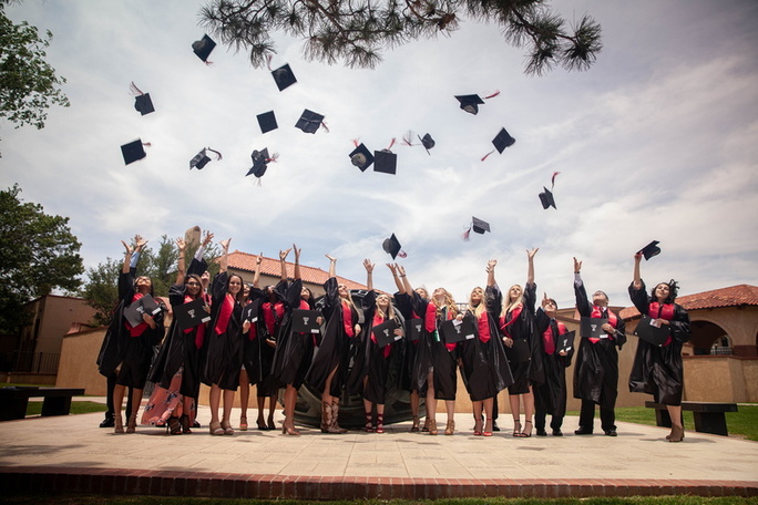 New graduates celebrate after the ceremony. Representatives of the 2018 TTU K-12 graduates toss their graduation caps into the air with outstretched arms as they stand on a concrete slab outside