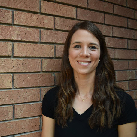 TTU K-12 Jessica Byrd standing in front of a brick wall while facing the camera and smiling