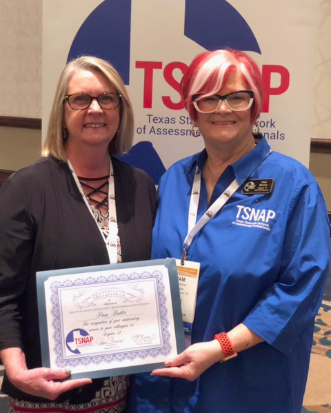 Pam Butler and Pam Brown face the camera smiling while both hold a recognition award and standing in front of a TSNAP retractable banner