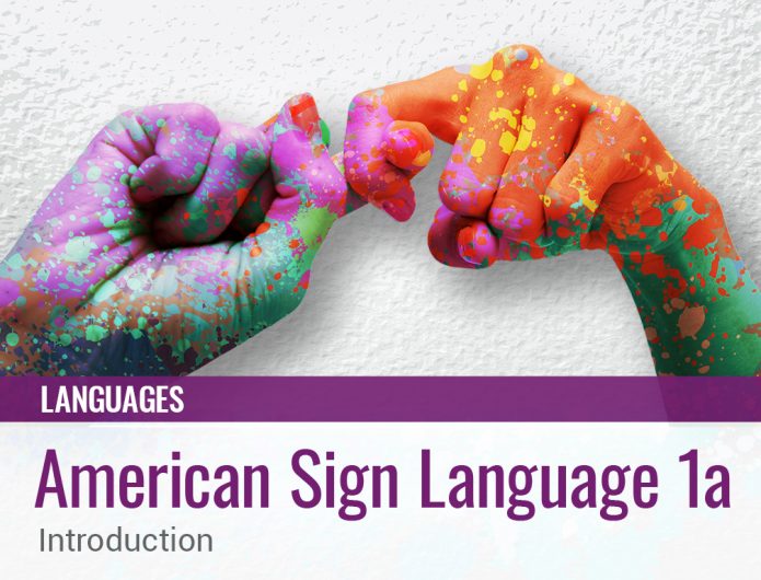 A pair of hands that are splotched yellow, orange, green, purple and teal while depicting a sign language sign