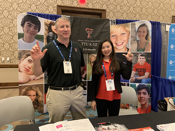 jared lay and victoria qin stand beside one another while displaying the guns up synbol and standing in front of a TTU K-12 tri-fold.