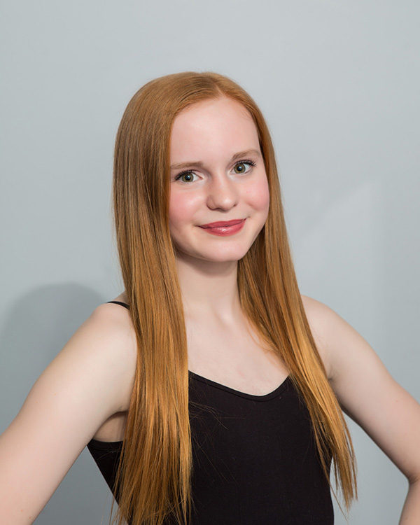 A headshot of Emma Gray smiling at the camera and wearing a black tank top