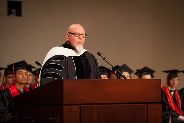 Todd Chambers stands behind a podium in front of graduates and addresses his audience.