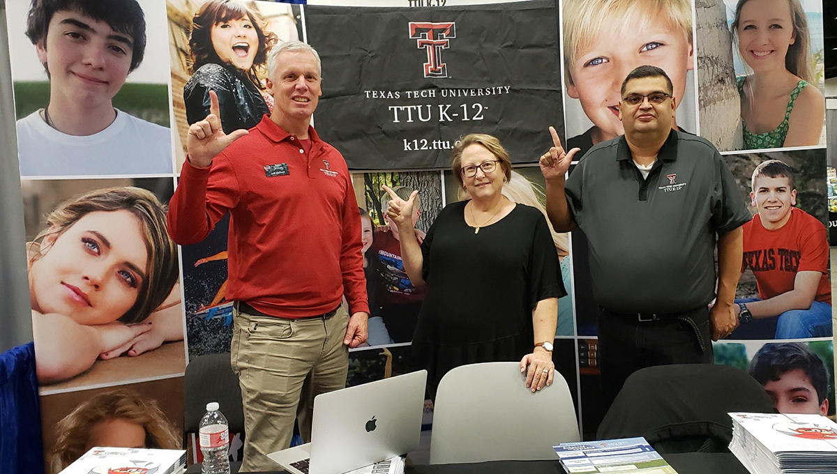 Jeff Oldham, Annette Coon and Israel Galvan represent TTU K-12 at the TCA Professional Growth conference in November A woman wearing a black blouse stands between two men as all three display the guns up symbol