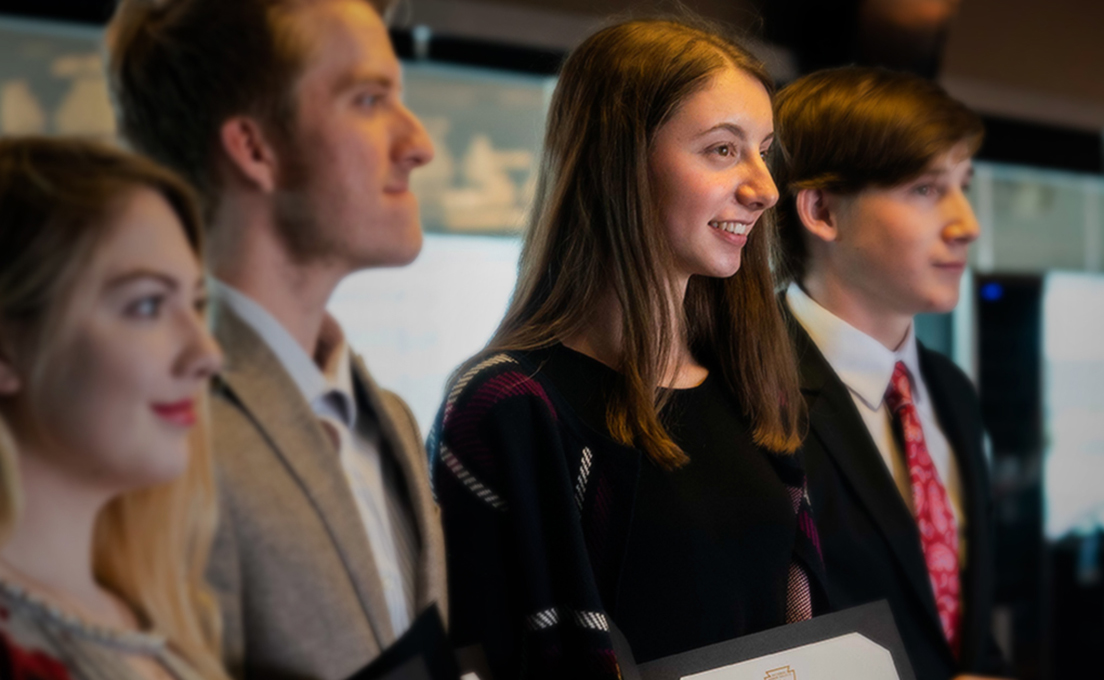 Rachel Koerner A young woman stands among two young men while looking off camera and smiling