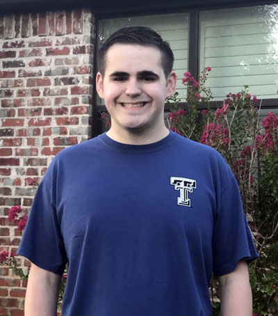 Grant Taylor, senior, has committed to attend Texas Tech University. A young man stands outside while smiling and wearing a navy blue shirt with a Texas Tech logo.