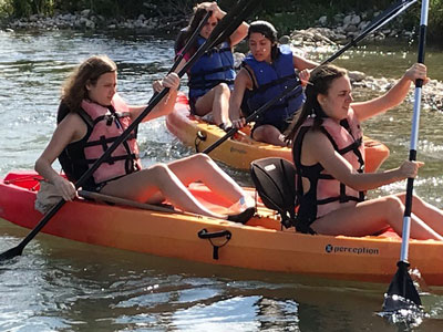 Summer camp atendees kayaking in a river.