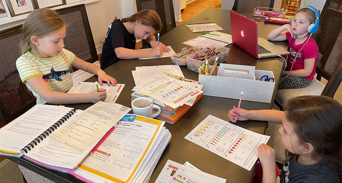 All four of the Smith sisters doing schoolwork at a table.