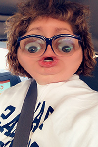 A woman's face through a Snapchat filter with brown hair and abnormally large eyes and a small mouth.