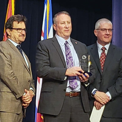 Jared Lay holding a Global Vision Award on stage.