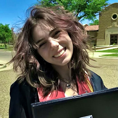 Lauren Thompson smiling in graduation ground with her diploma.