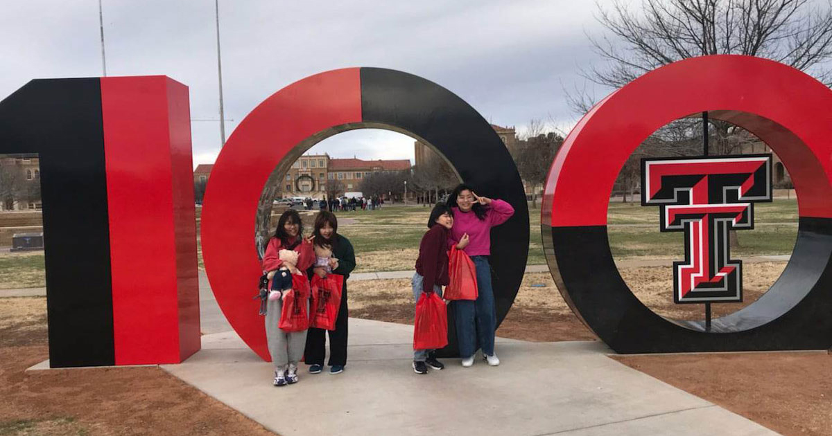 Four South Korean TTU K-12 middle school students in front of the Texas Tech University Centenial art installation on the Lubbock campus