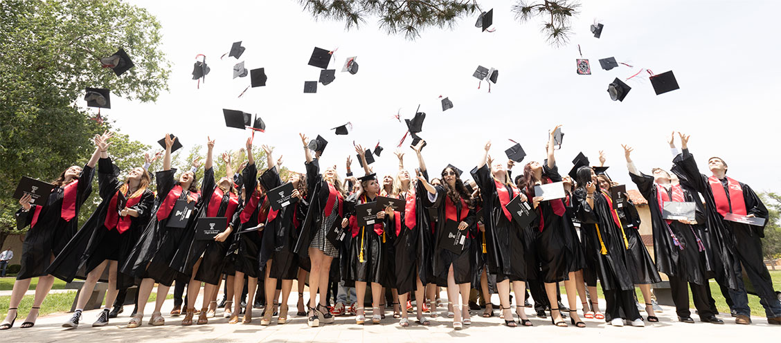 2023 TTU K-12 graduates throwing mortarboards in the air.