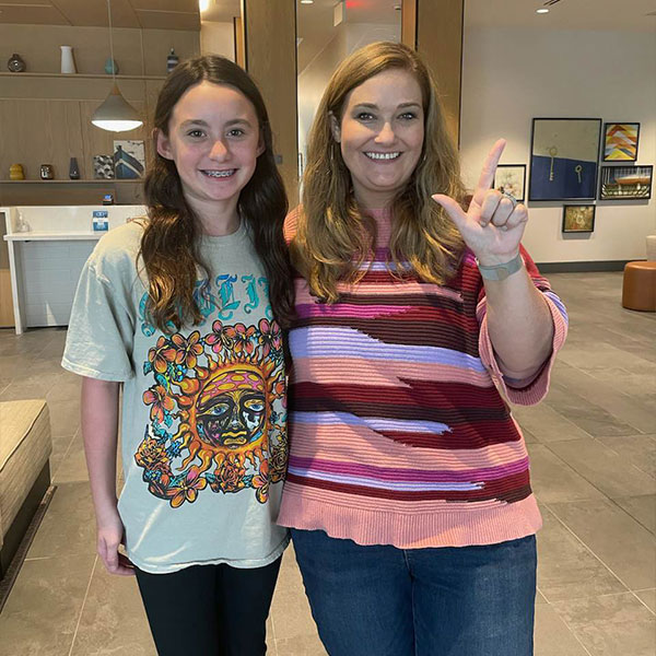 Test taker with principal giving guns up hand sign.