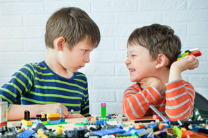 Boys playing together, one scowling while the other laughs.