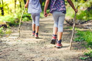 Kids walking a hiking trail, one leading the other.