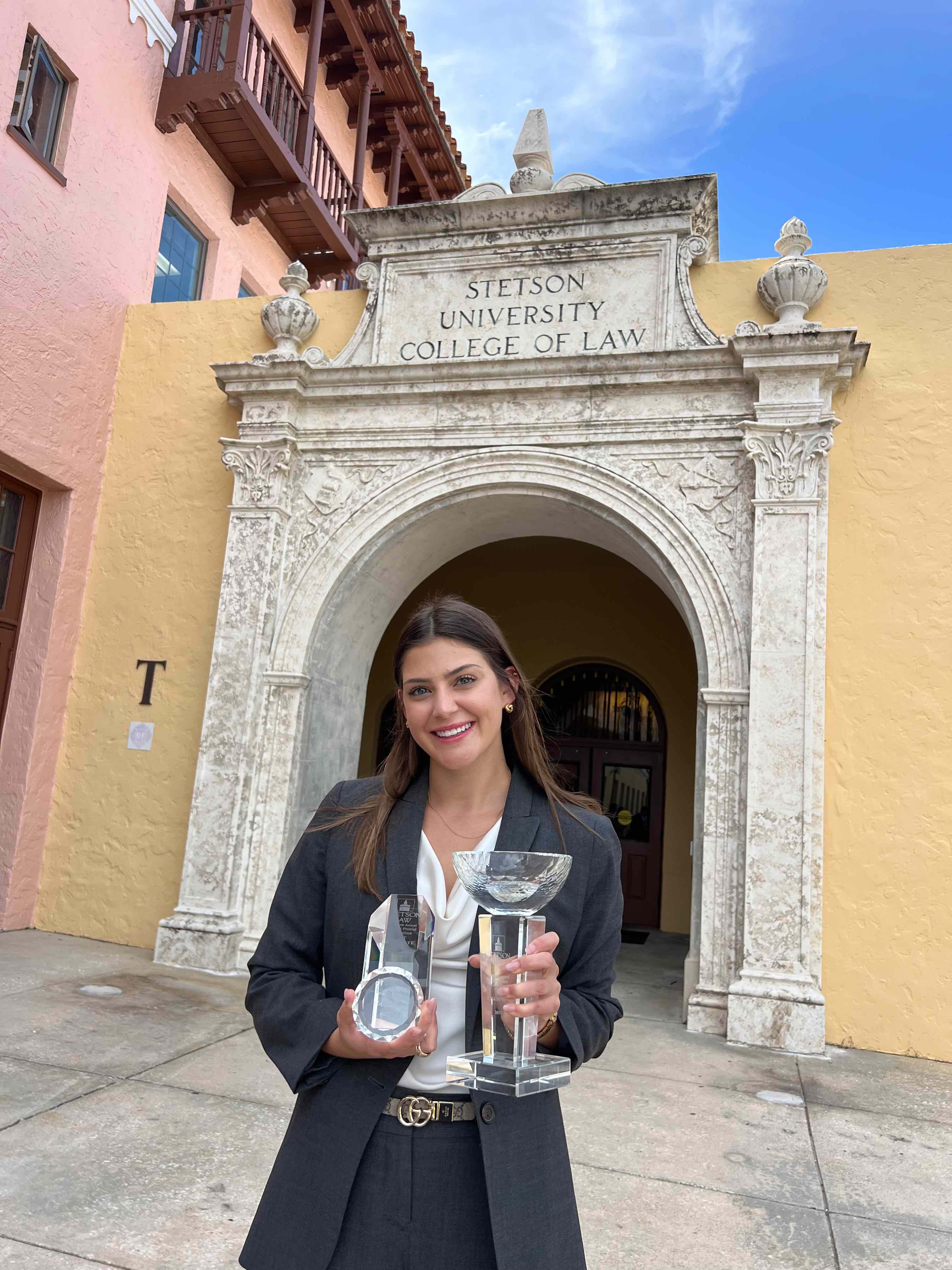 Rachel Behnke holding the championship trophy and Overall Best Advocate trophy after the competition.