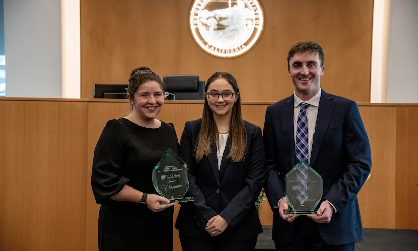 Three Texas Tech Law students—Sophia Jenkins, Kiera Figgins, and Grant McClure—stand together holding championship trophies after winning the Chapman, Lewis Clark Moot Court Invitational.