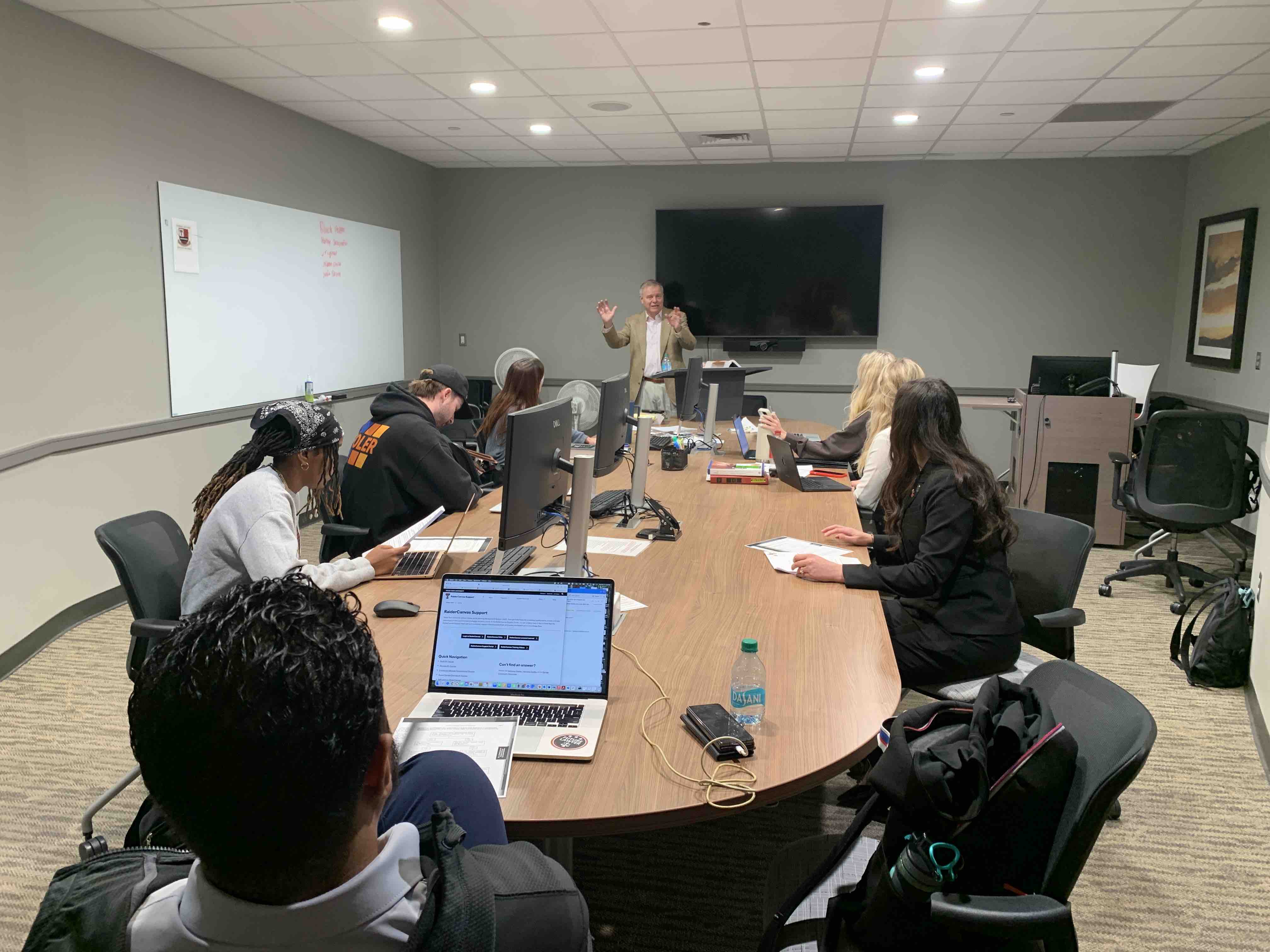 View from the back of a classroom showing Professor Mark “Max” Maxwell teaching Texas Tech law students in the Veterans Law Clinic.